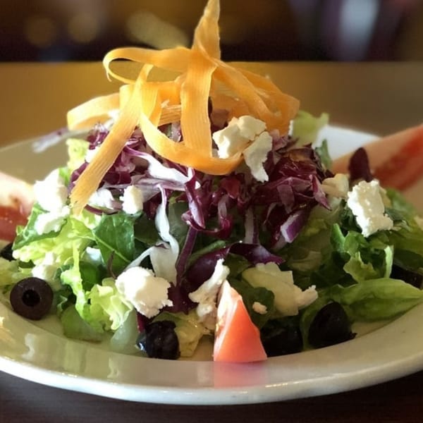 Fresh Italian salad with mixed greens, feta cheese, black olives, tomatoes, and carrot ribbons.