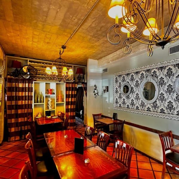 Warmly lit dining room at Michelangelo Ristorante with wooden tables, chairs, and decorative chandeliers.