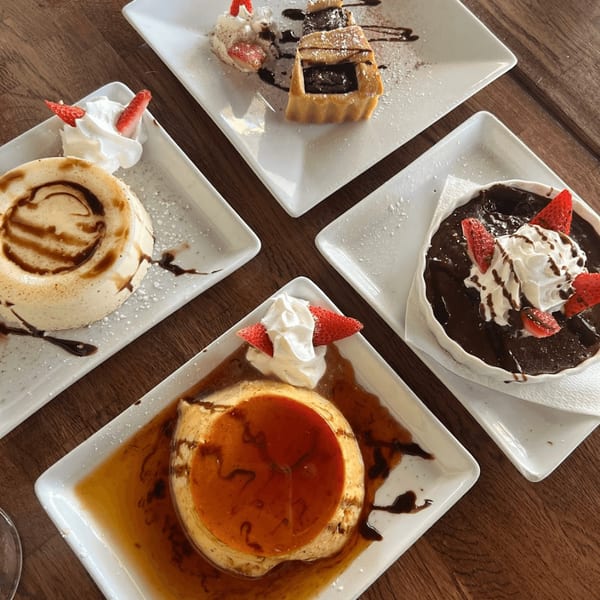 Four Italian desserts, including flan, chocolate lava cake, and a tart, on a wooden table.