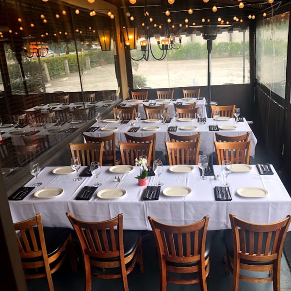 An empty outdoor dining patio at Michelangelo Ristorante, with set tables and string lights overhead.