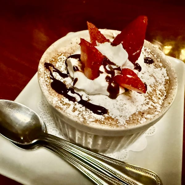 Italian dessert with whipped cream, strawberries, chocolate drizzle, and powdered sugar in a white ramekin.