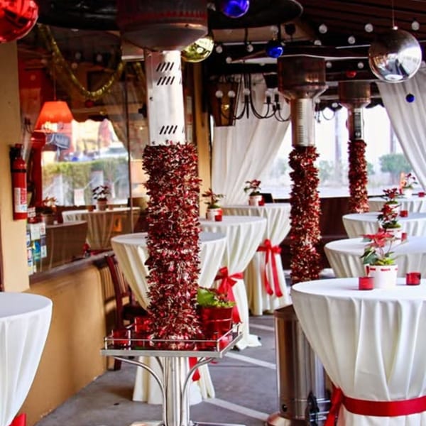 Outdoor patio at Michelangelo Ristorante decorated for a festive event with white tables and red accents.